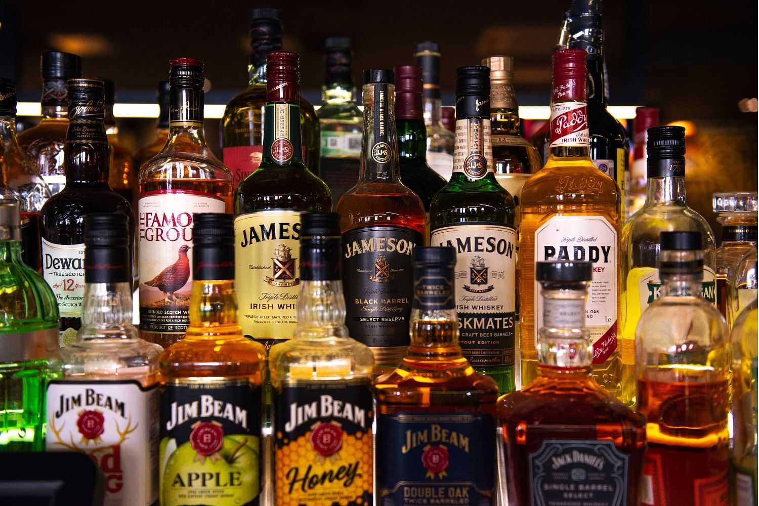 Assorted whiskey and liquor bottles on a bar shelf.
